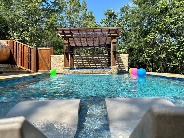 Una piscina con cubierta de madera y una pérgola.