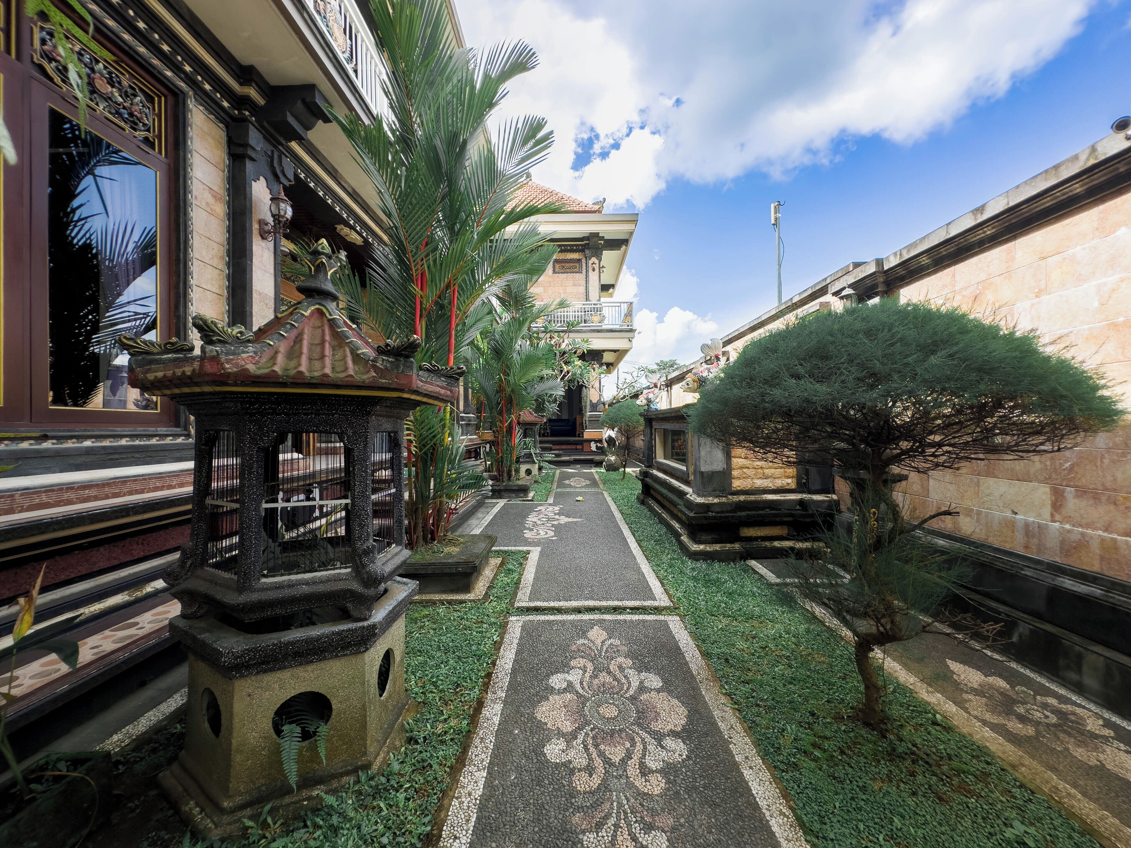 A pathway lined with decorative planters and a patterned pavement, leading to a building with a traditional architectural style.