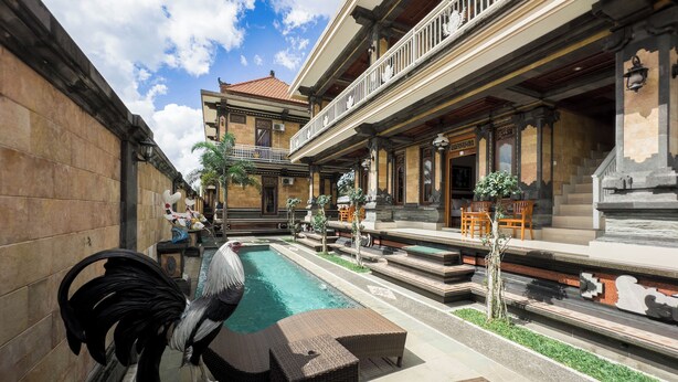 A courtyard with a swimming pool, outdoor seating, and a traditional building with a tiled roof. - Tiara Guest House Ubud (Ubud)
