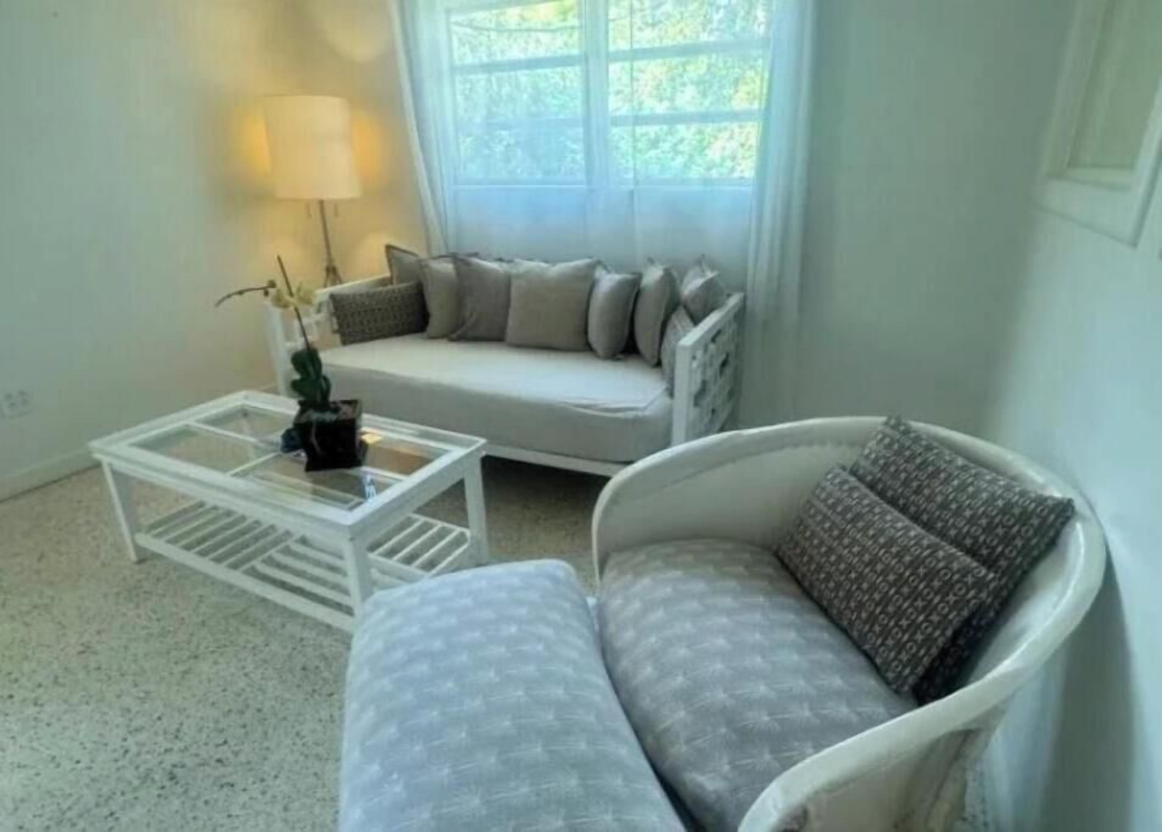 A living room with a sofa, a chair, a coffee table, and a lamp.