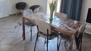A dining area with a large table, chairs, a vase with flowers, and a view of the outdoors through a window. - Top of villa in charming Provencal village (La Crau)