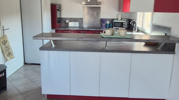 A modern kitchen with a central island, stainless steel appliances, and red accents. - Top of villa in charming Provencal village (La Crau)