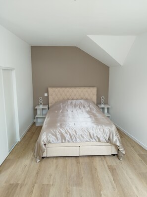 A bedroom with a bed, a sloped ceiling, and a wooden floor. - Aurore's cottage (Pernant)