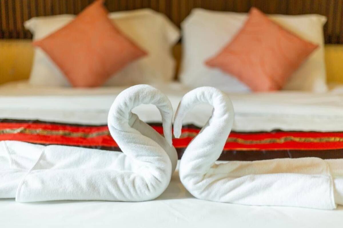 Ein Bett mit weißen Bettwäsche und zwei rosafarbenen Kissen.