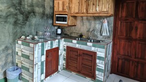 A compact kitchen with wooden cabinets, a microwave, and a tiled backsplash. - Phanumas LongStay Resort  (San Pa Thong)