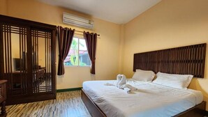 A hotel room with a bed, wooden headboard, curtains, and a window. - Phanumas LongStay Resort  (San Pa Thong)