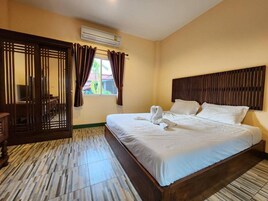 Quarto de hotel com cama, cabeceira de madeira, cortinas e janela.