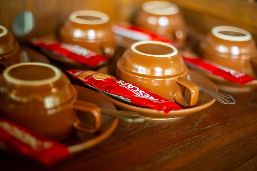 A table with several ceramic cups and saucers, some with red packaging.