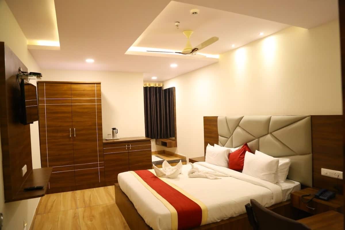 A hotel room with a bed, bedside tables, a wardrobe, a ceiling fan, and a TV.