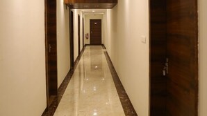 A hotel corridor with a marble floor, wooden doors, and recessed lighting. - Hotel M Grand (Hyderabad)