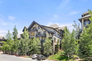 A multi-story residential building with balconies, surrounded by trees and a clear sky. - Stunning Capitol Peak Condo! Steps to Dining & Trails in Base Village.  Hot Tubs, A/C, W/D, Parking (Snowmass Village)