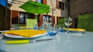 An outdoor dining area with a table set for two, featuring a green umbrella, clear glassware, and yellow napkins. - House in Périgord near Medieval Villages (Prats du Périgord)