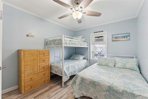 A room with bunk beds, a wardrobe, a ceiling fan, and a window with blinds.