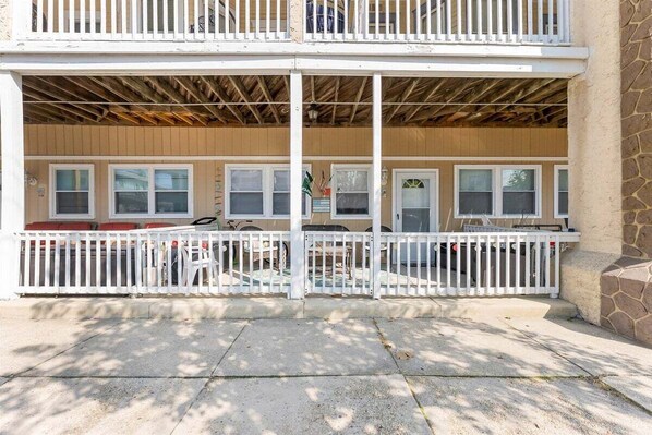 A two-story building with a covered porch, wooden siding, and a white fence. - Modern 2 Bedroom Condo with Pool (Wildwood Crest)