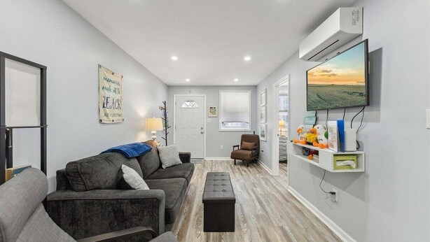 A living room with a sofa, a coffee table, a TV, and a wall-mounted shelf with toys. - Modern 2 Bedroom Condo with Pool (Wildwood Crest)
