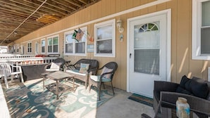 A covered outdoor seating area with wicker furniture, a patterned rug, and a door with windows. - Modern 2 Bedroom Condo with Pool (Wildwood Crest)
