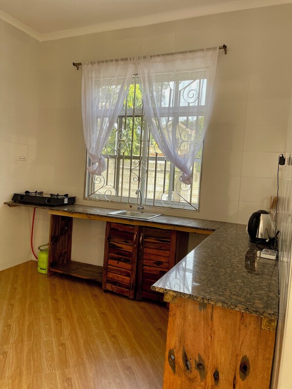 Una cocina con ventana, armarios de madera, encimera y estufa a gas.