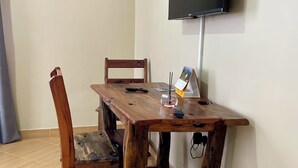 Un coin repas avec une table et des chaises en bois, un téléviseur fixé au mur et une poutre en bois sur le mur.