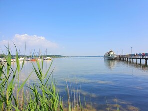 Um areal tranquilo com um cais que se estende sobre a água, rodeado por vegetação e barcos.
