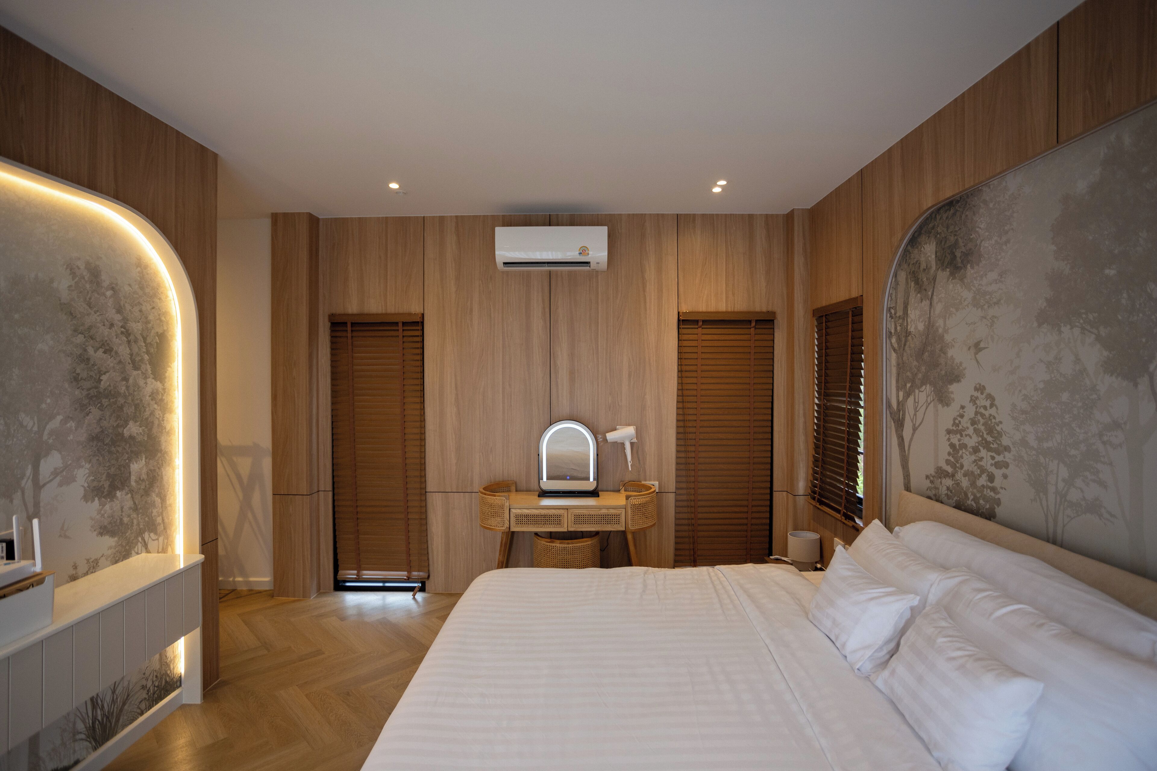 Ein modernes Schlafzimmer mit einem großen Bett, einem Schminktisch mit Spiegel und einer Klimaanlage an der Wand.