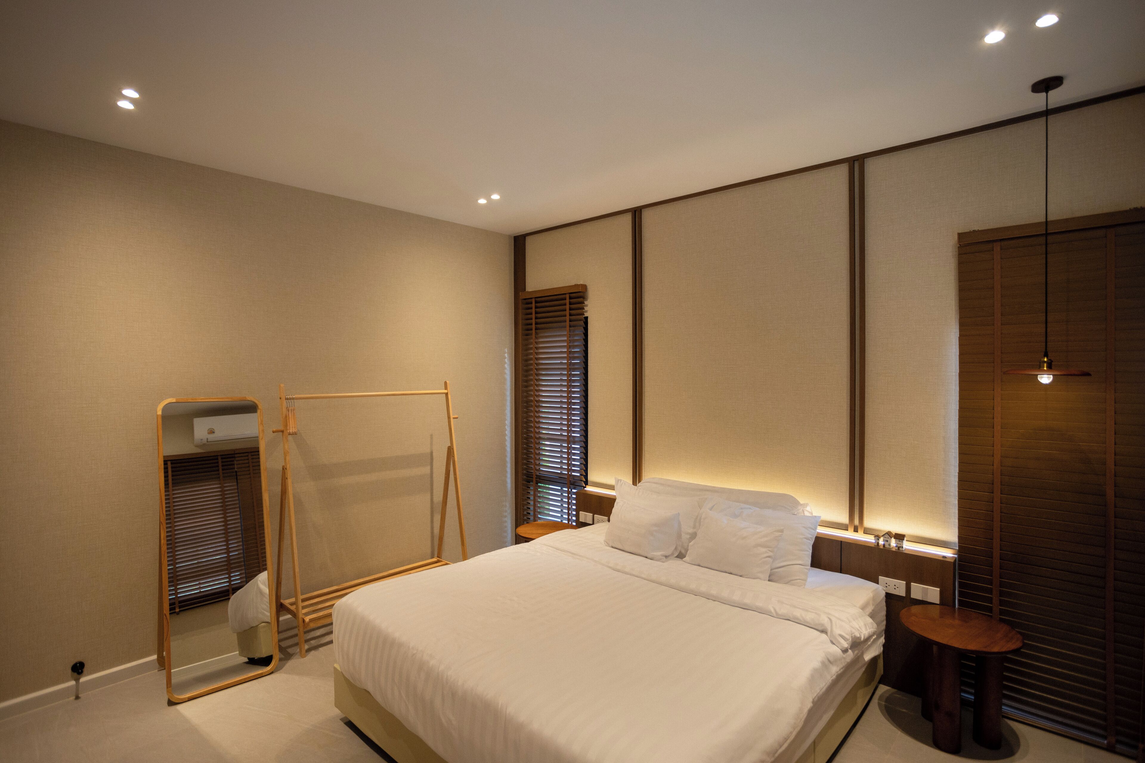 A modern bedroom with a large bed, bedside tables, a mirror, and a wardrobe.