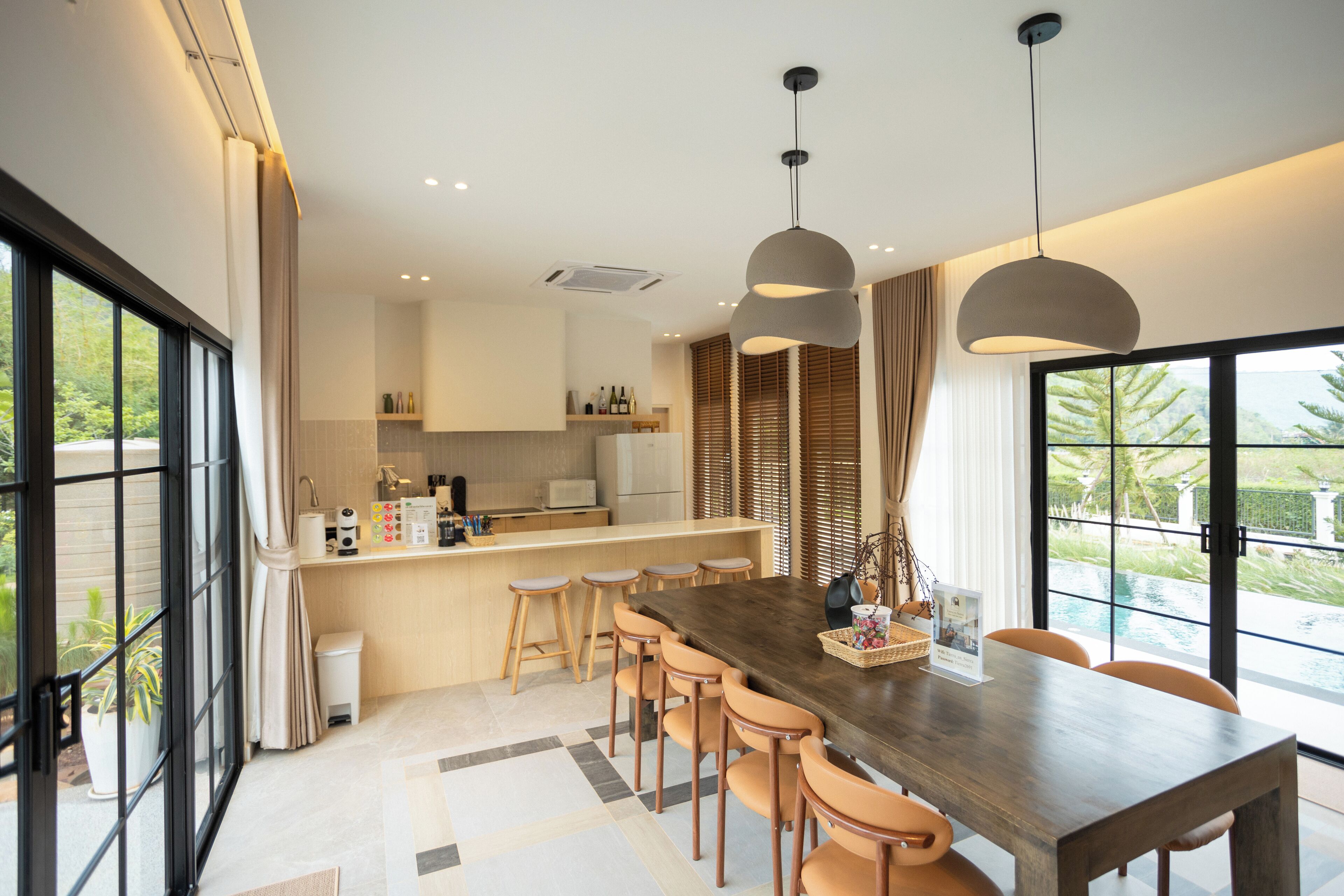 A modern kitchen with a central island, bar stools, and pendant lighting.