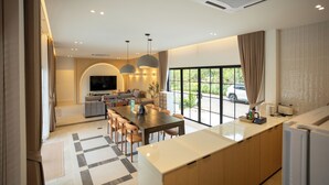 A modern kitchen with a large island, a dining area with a checkered rug, and a living room with a TV and seating. - Tierra en Sierra (Pak Chong)