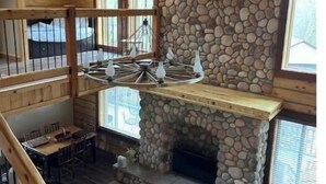 Un ambiente spazioso con camino in pietra, travi in legno e zona pranzo.