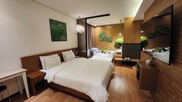 A modern hotel room with a large bed, a desk, and a seating area.
