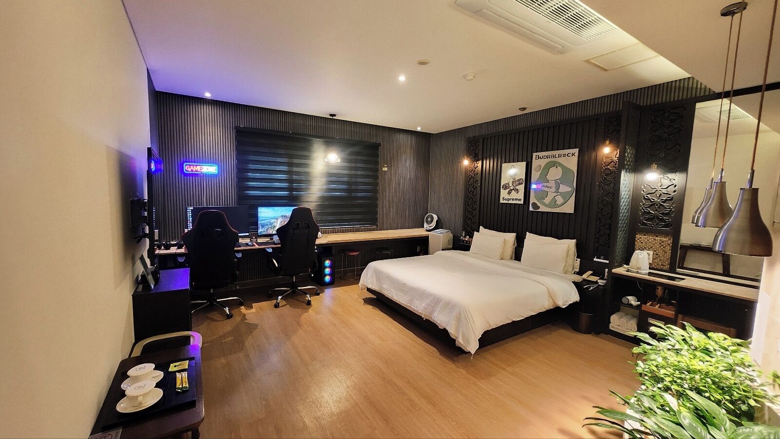Una habitación de hotel moderna con una cama grande, un escritorio con dos sillas, una computadora y un televisor.