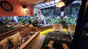A cozy indoor seating area with a large aquarium, comfortable sofas, and a view of a waterfall through a glass wall. - Polo Hotel (Incheon)