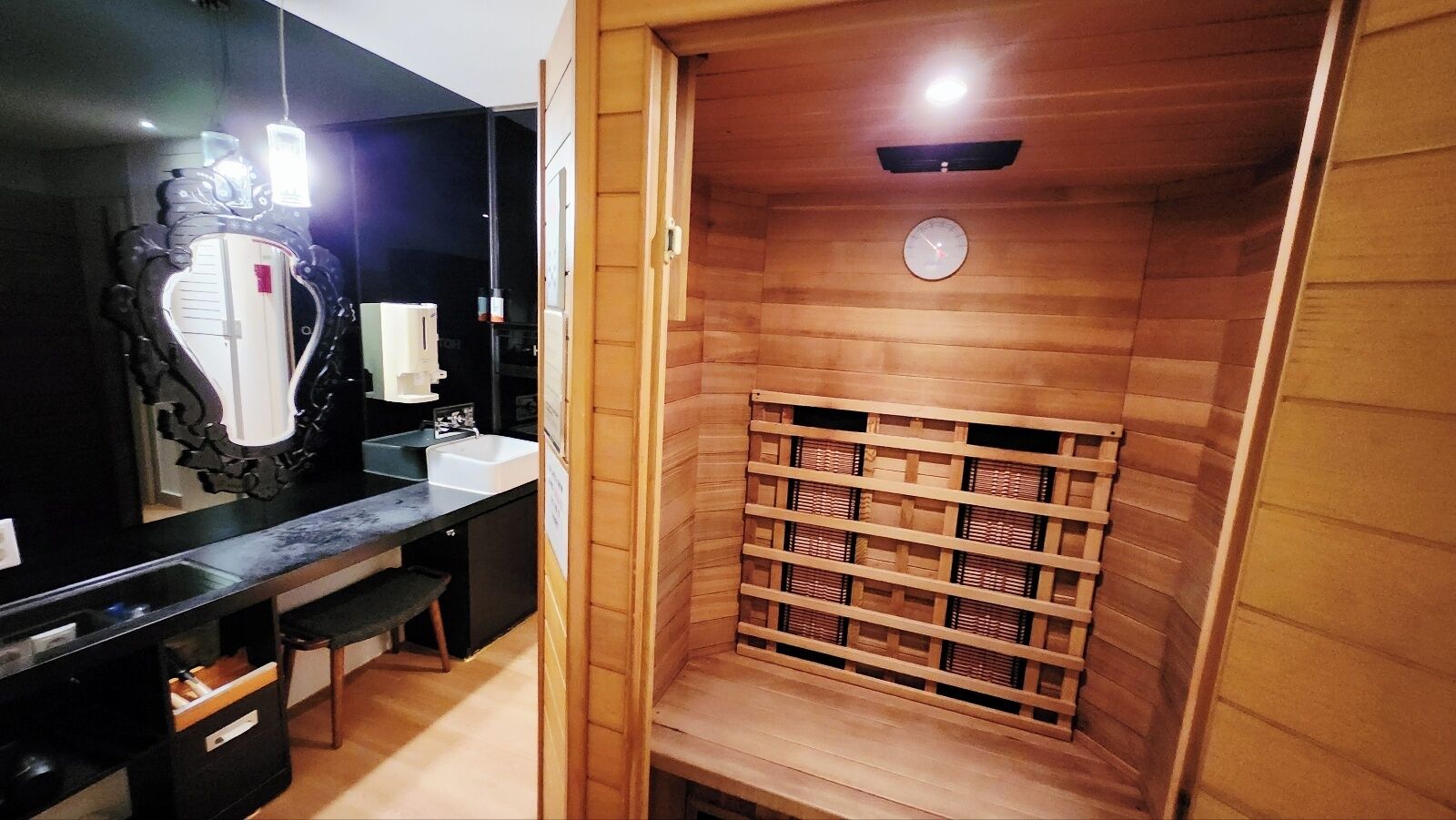 A bathroom with a wooden vanity, a mirror, a sink, and a shower area with a wooden shelf.