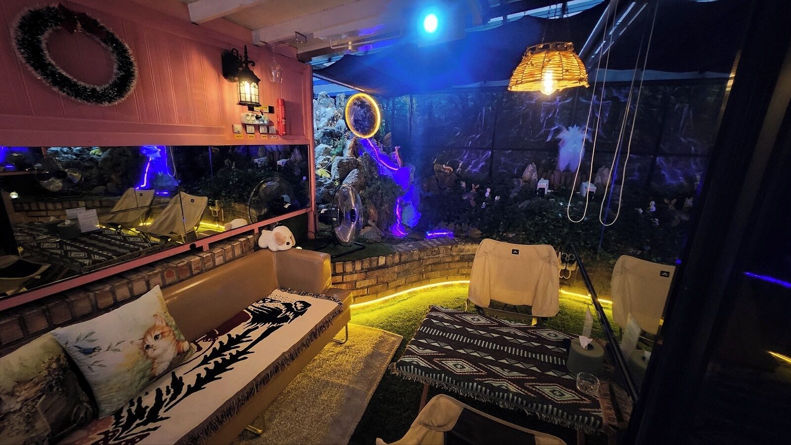 A cozy lounge area with a sofa, chairs, and a small table. There is a decorative wall with a wreath and a lantern.