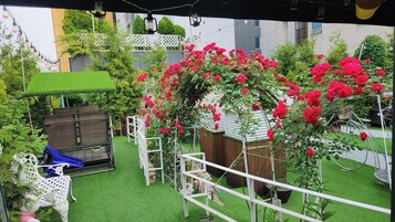 Un jardin avec une pelouse artificielle, un banc en bois, une chaise blanche et une balançoire.