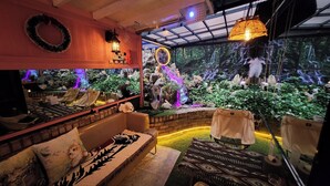 A cozy indoor space with a sofa, a small table, and a decorative wall with a waterfall display. - Polo Hotel (Incheon)