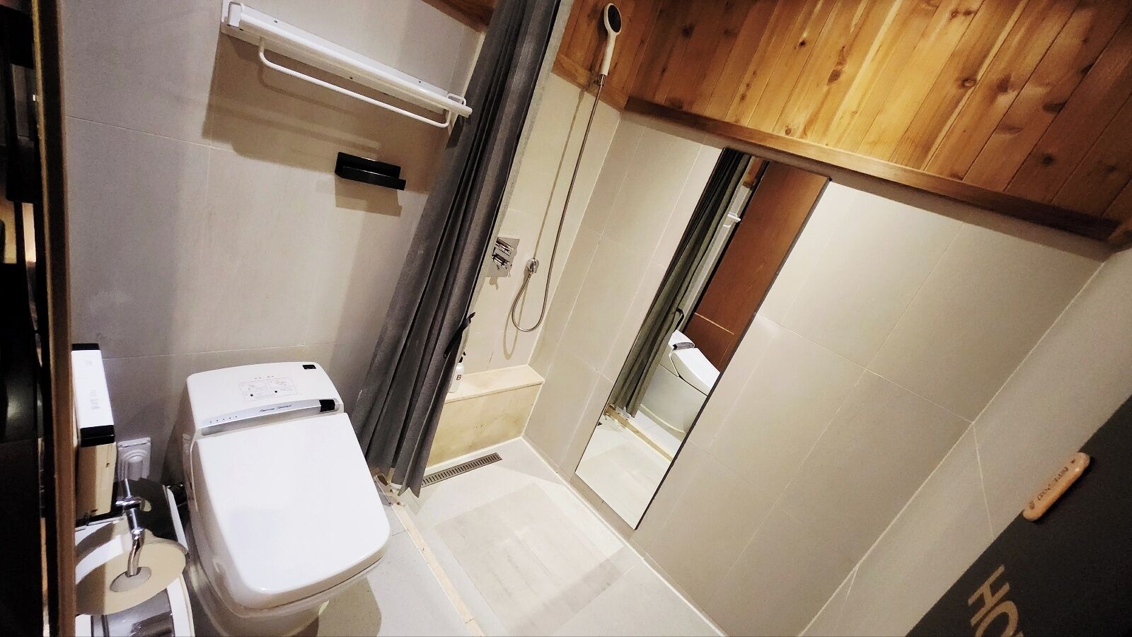 Ein kleines Badezimmer mit Toilette, Duschbereich und Holzboden.