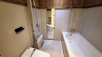 A modern bathroom with a bathtub, shower, and toilet.