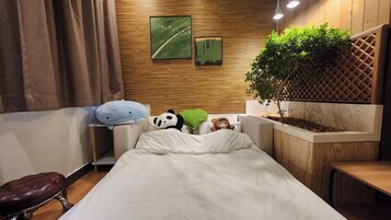 A neatly arranged bedroom with a bed, a small table, a chair, and a potted plant.