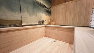 A minimalist wooden interior with a painting of a landscape on the wall, a small wooden stool, and a metal container on the counter.