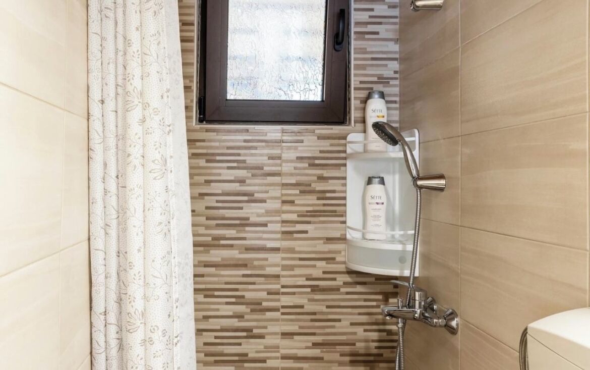 Un bagno con doccia, una finestra e un portascopevoli.
