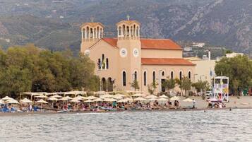 Une église côtière dotée d’un clocher, entourée de parasols de plage et de personnes.
