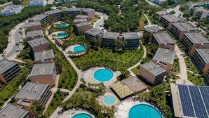 An aerial view of a resort with multiple swimming pools surrounded by palm trees and modern buildings. - Algarve Golf & Golden Coast by Interhome (Gale)