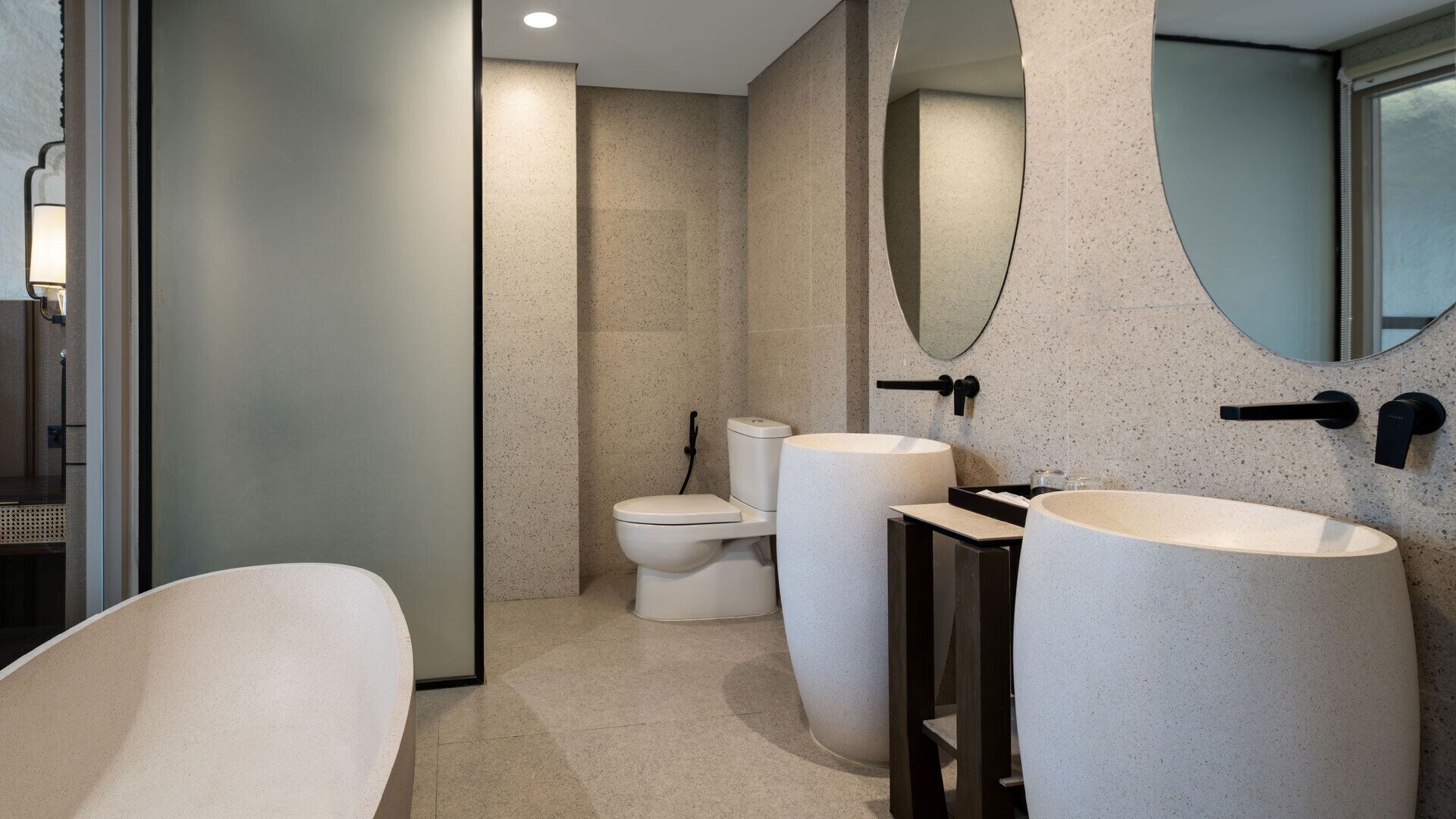 Un baño moderno con una bañera independiente, un inodoro y un lavabo con un espejo grande arriba.