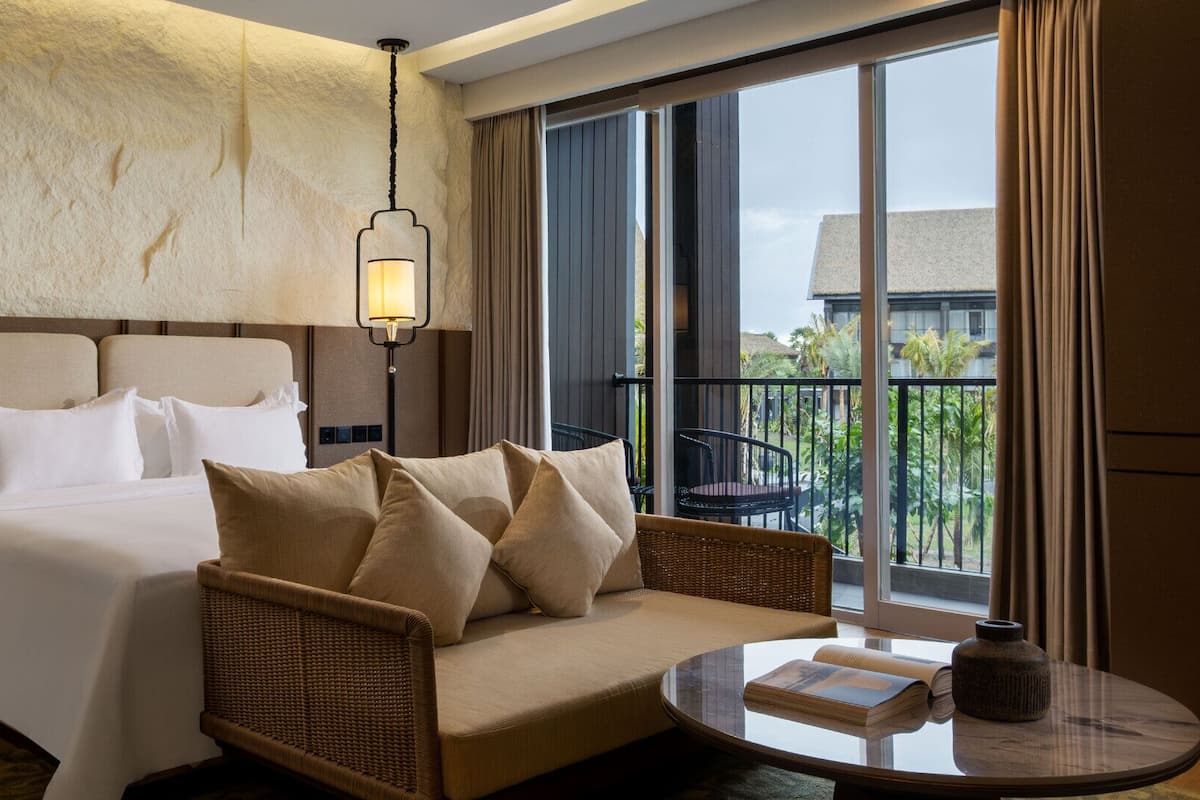 Una habitación de hotel con cama, sofá, mesa y balcón con vistas.