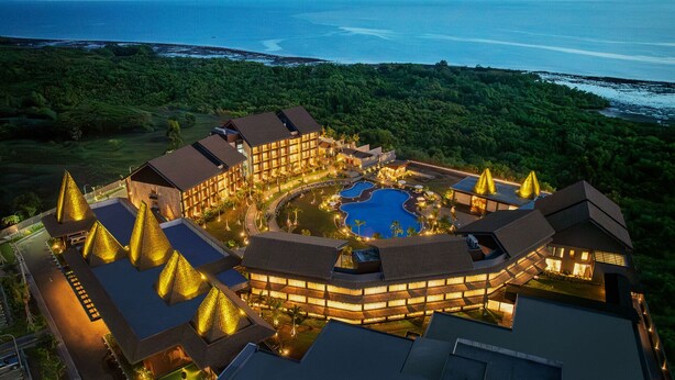 Un resort con una piscina central, varias edificaciones de diseño moderno y un exuberante paisaje verde circundante.
