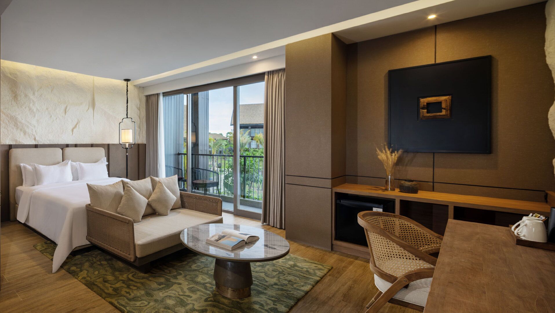 A modern hotel room with a bed, sofa, and a small dining area.