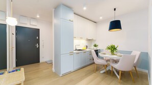 A modern kitchen with light blue cabinets, a white countertop, and a dining area with a round table and four chairs.