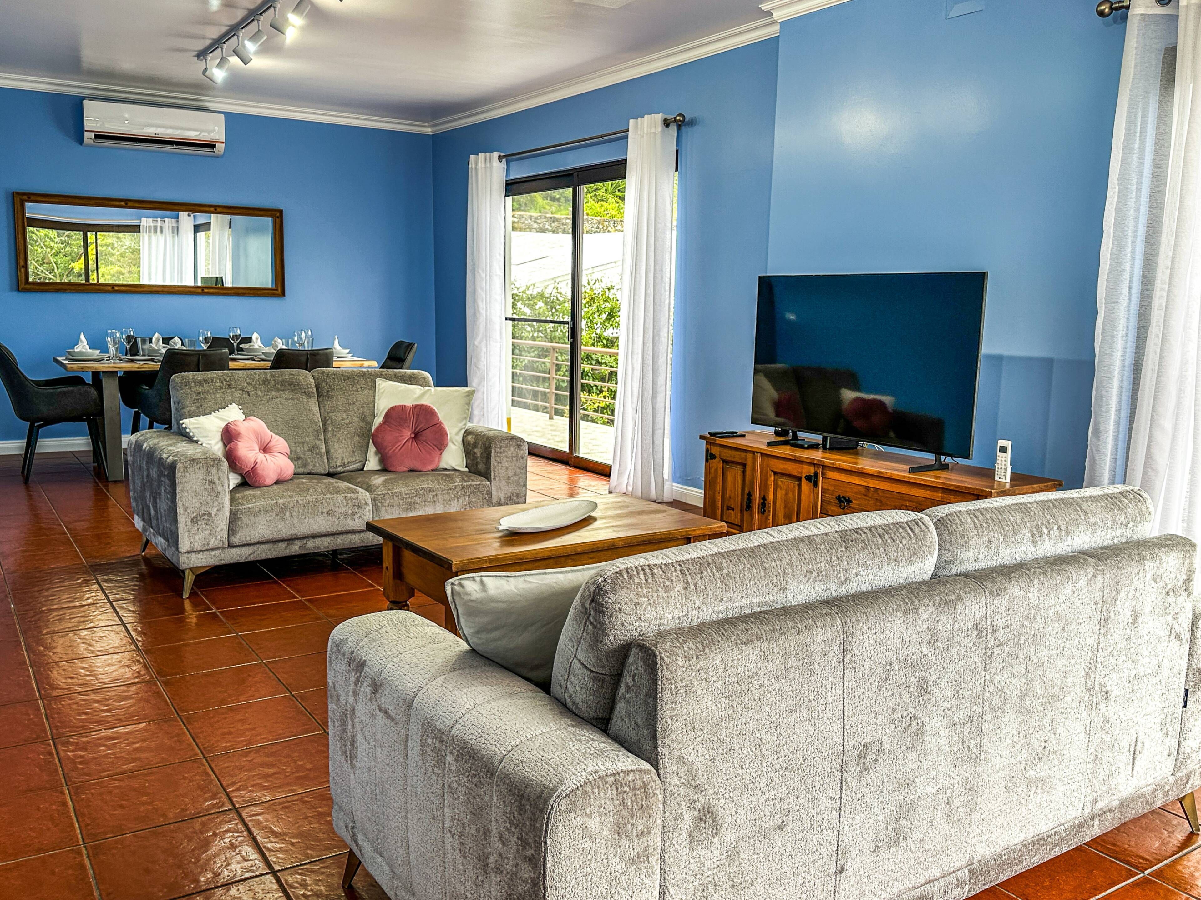 A living room with blue walls, a dining area, and a TV.