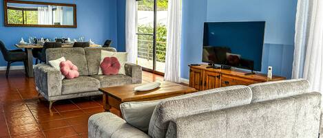 A living room with blue walls, a dining area, and a TV.