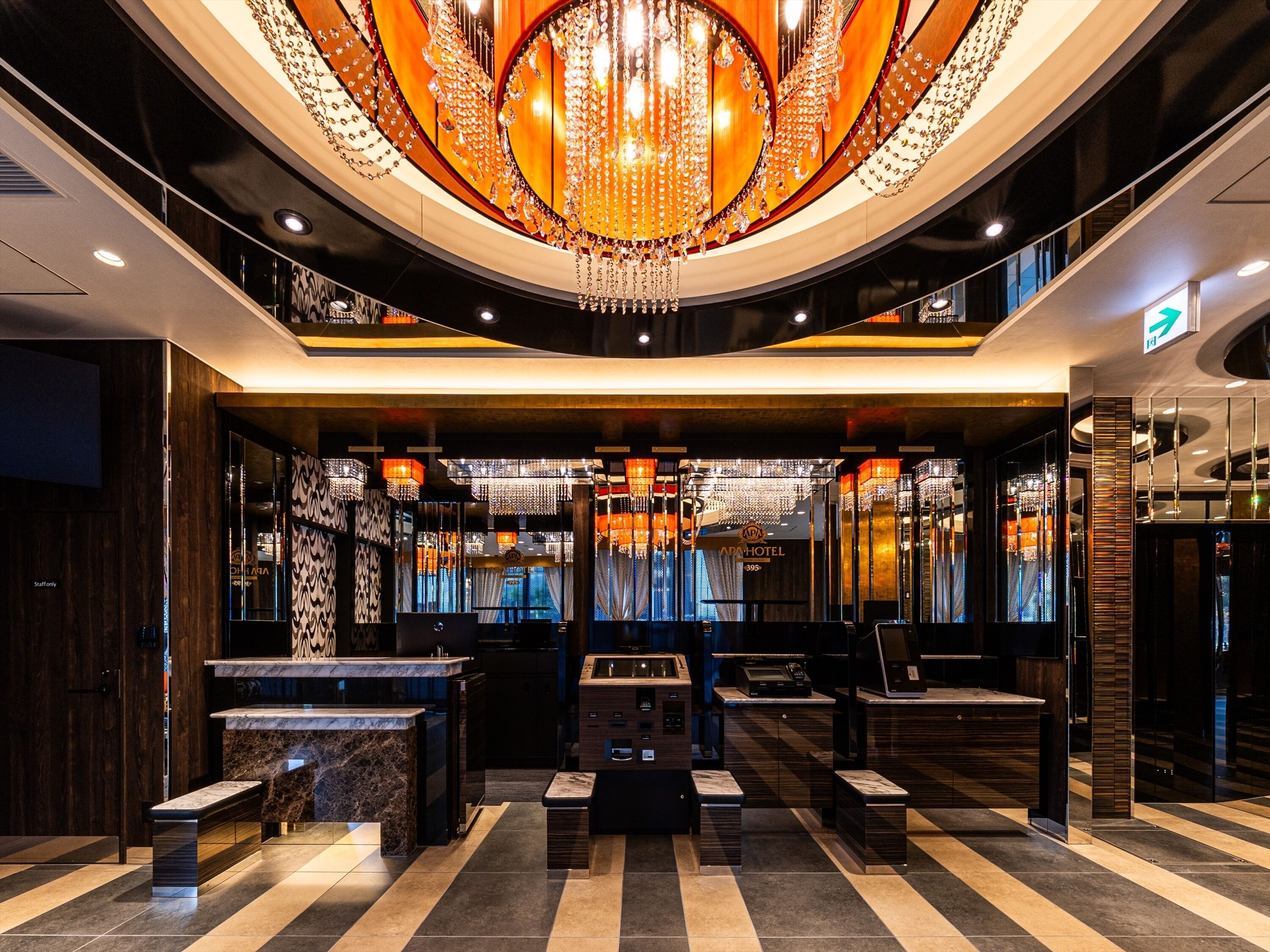 A hotel lobby with a grand chandelier, marble reception desk, and modern decor.